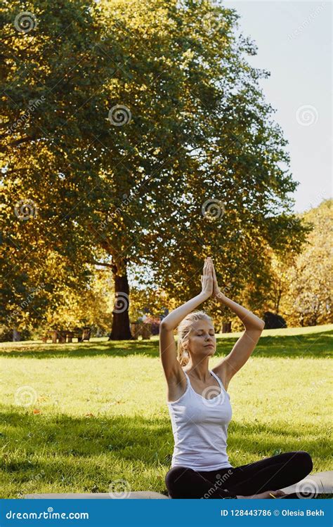 Girl Meditates While Practicing Yoga Outdoors In Park Stock Photo
