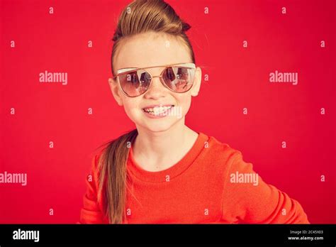 Portrait Of Brunette Girl Wearing Red T Shirt And Sunglasses On Red