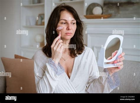 woman massages her face with pink stone roller facial massage at home spa facial treatment