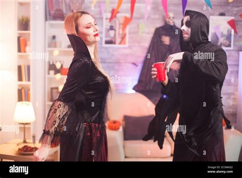Man Dressed Up Like A Grim Reaper Dancing With Beautiful Vampire Woman At Halloween Celebration