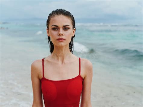 Beautiful Woman In A Red Swimsuit Looks At The Camera On The Ocean