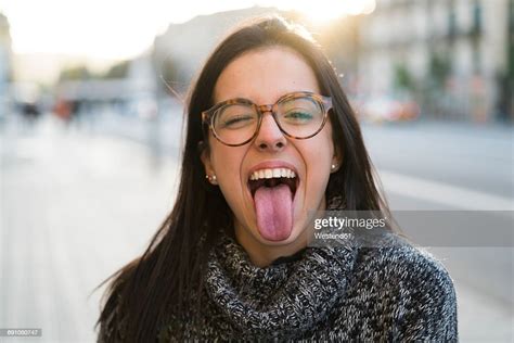 Portrait Of Happy Young Woman With Glasses Sticking Her Tongue Out