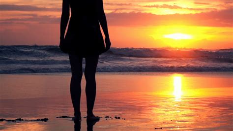 Silhouette Of Beautiful Woman Standing On The Beach During Sunset