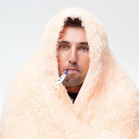 a sick man wrapped in a blanket holds a thermometer in his mouth stock image image of person