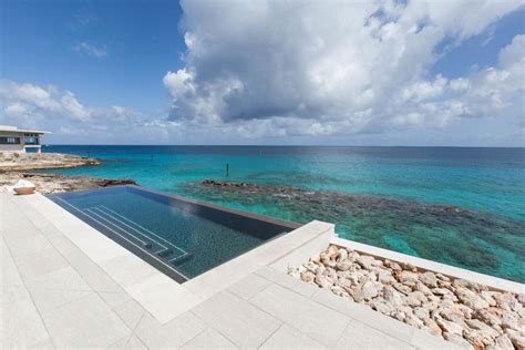 an outdoor swimming pool on the edge of a cliff overlooking the ocean and coral reefs