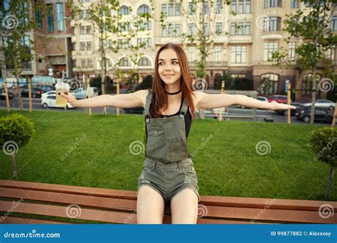 une jeune fille s assied sur un banc dans la ville avec une boisson dans son ha photo stock