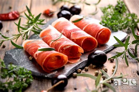 Sliced Prosciutto With Herbs And Olive Stock Photo Picture And Low