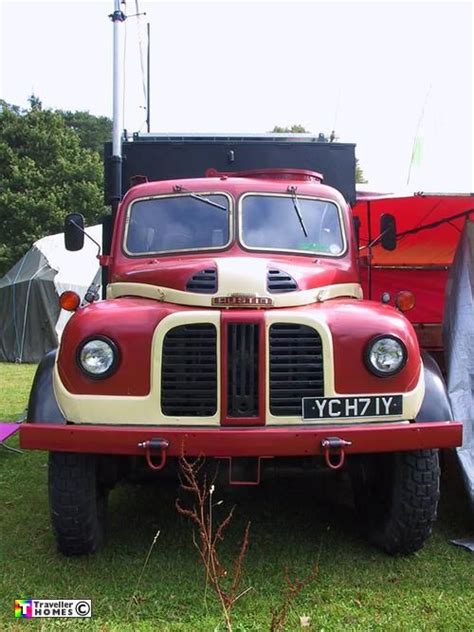 An Old Red And White Truck Parked In The Grass Next To A Tent On Top Of