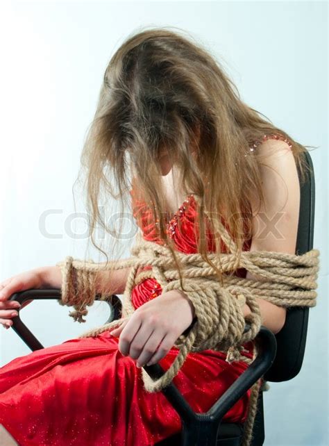 Woman Tied Up With A Rope Against Light Background Stock Photo