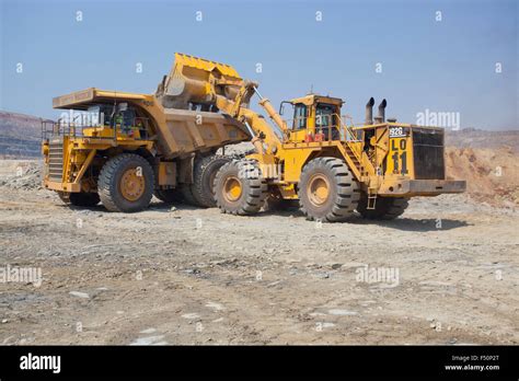 Action Shot Of A Front End Loader Filling A Large Haul Dump Mine Truck