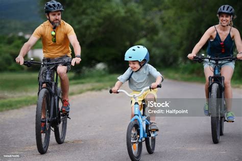 Młoda Rodzina Z Małym Dzieckiem Jeżdżąca Na Rowerach Po Drodze W Wiosce
