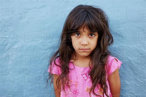 Close Up Portrait Of Innocent Little Girl Standing Against Blue Wall
