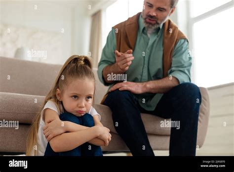 Strict Father Scolding Sad Little Daughter Sitting At Home Stock Photo
