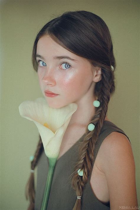 A Woman With Braids And Blue Eyes Holding A Flower In Front Of Her Face