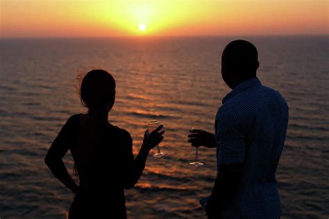 Silhouette Of Happy Couple Standing Near The Sea And Take A Photo