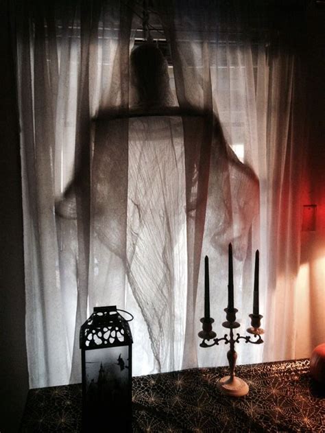 A Ghostly Woman Standing In Front Of A Sheer Curtain With Candles On