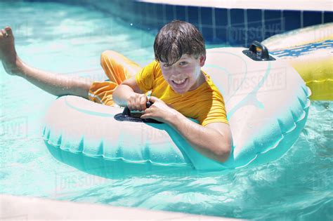 Hispanic Boy Floating On Raft In Swimming Pool Stock Photo Dissolve