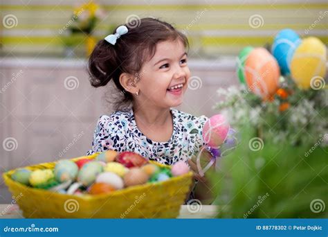 Cute Little Girl With Basket Full Of Colorful Easter Eggs Stock Photo