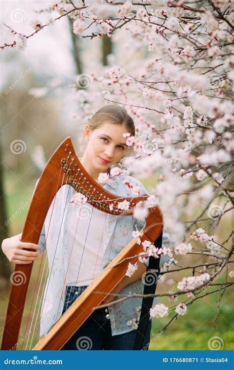 Woman Harpist With Harp Among Spring Flowering Garden Stock Image