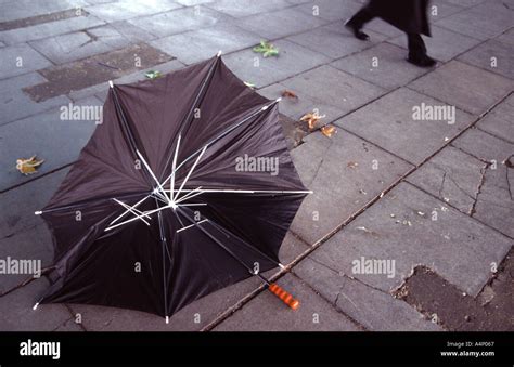 Man Walking Past A Broken Umbrella In An Autumnal Storm And Bad Weather
