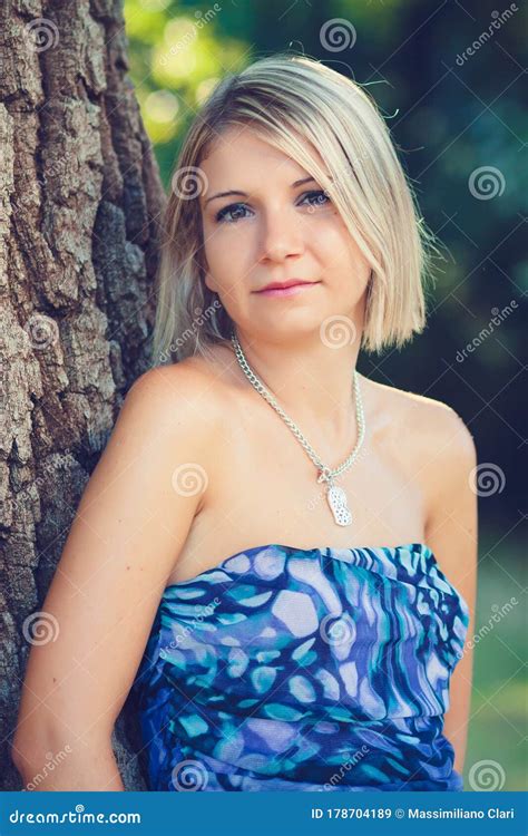 Portrait Of Fashionable Young Sensual Blonde Woman In Garden Lean On
