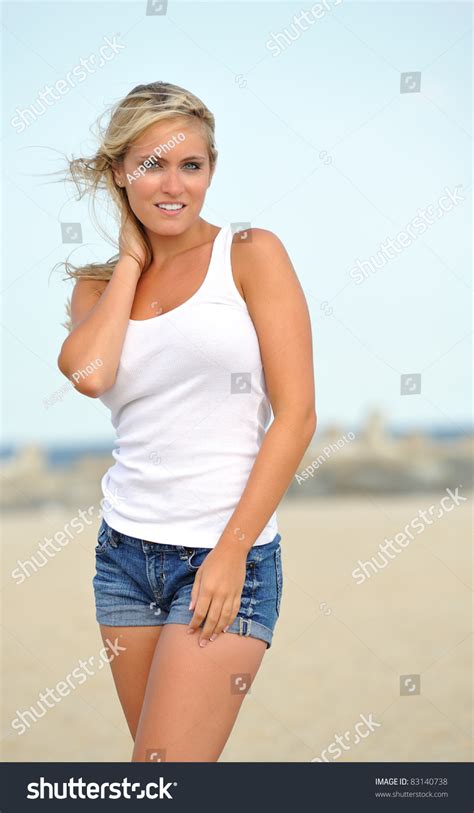Beautiful Young Blonde Woman In White Tank Top And Denim Shorts Posing