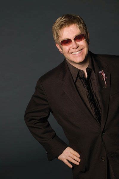 A Man In A Black Suit And Sunglasses Posing For A Photo With His Hands