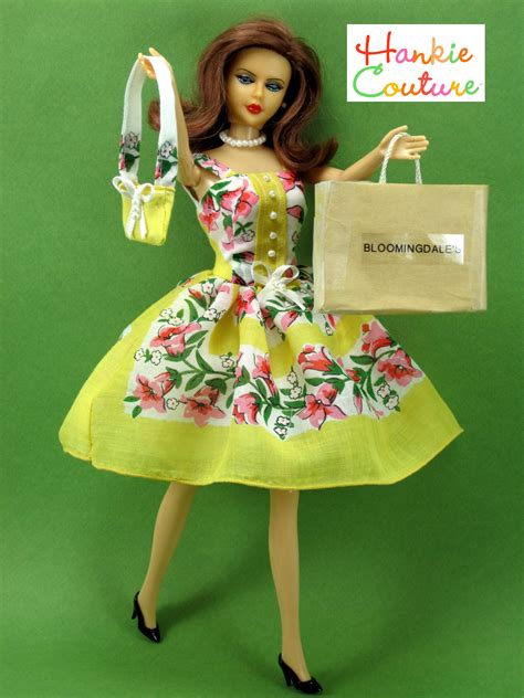 a barbie doll holding a shopping bag and wearing a yellow dress with flowers on it