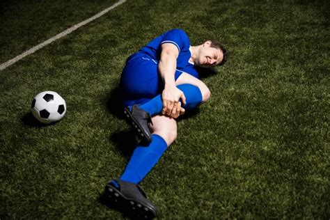 Injured Soccer Player Lying On The Ground And Holding His Leg During A