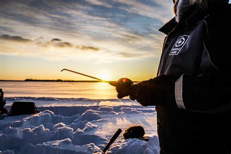 Ice Fishing On A Frozen Lake Beyond Arctic Rovaniemi