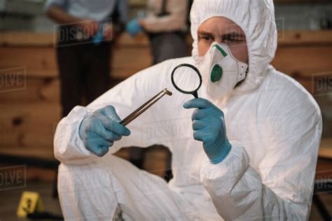 Close Up Of Forensic Investigator Examining Evidence With Magnifying