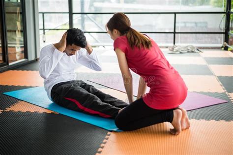 Sportsman Sit Ups In Gym With Assistance Of Female Friend In Gym Stock