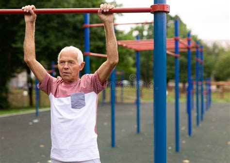 Elderly Man Hanging From Pullup Bar And Doing Pull Ups Stock Image