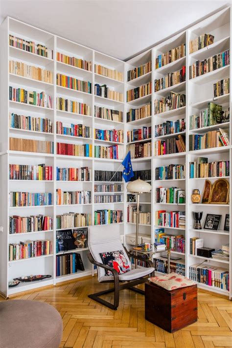 A Living Room Filled With Lots Of Books On White Bookcases Next To A