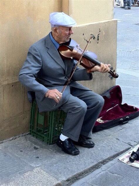 an old man sitting on a bench playing the violin