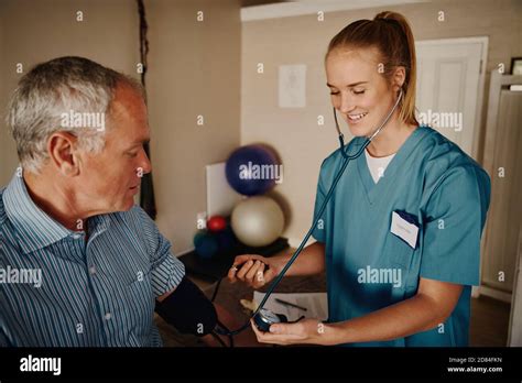 Smiling Young Woman Doctor Checking Senior Patient Blood Pressure Using