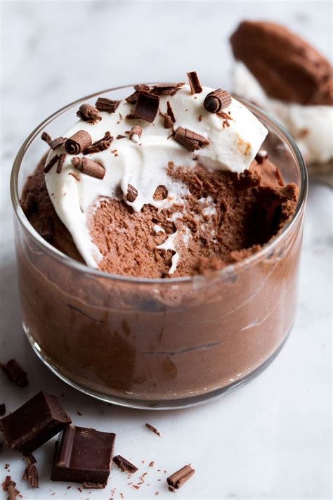 A Chocolate Dessert With Whipped Cream And Chocolate Chunks On The Side In A Glass Bowl