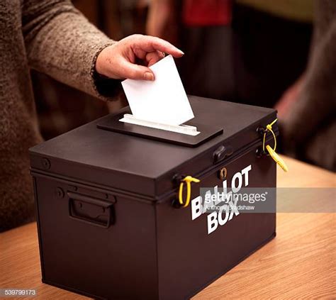 Person Places Their Vote In A Ballot Box At A Polling Station St Francis School