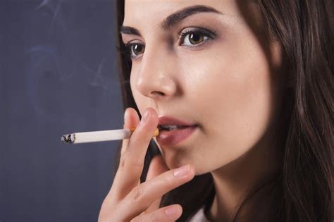 Premium Photo Young Woman Smoking Cigarette On Dark Background