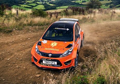 An Orange Car Driving Down A Dirt Road