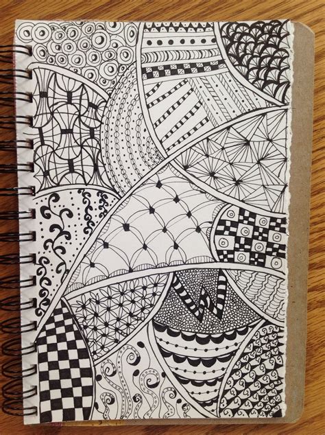 A Spiral Notebook With Black And White Doodles On It Sitting On Top Of