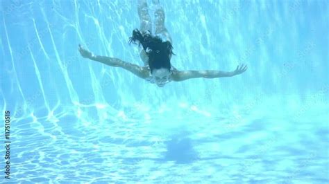 Stockvideo Girl Swimming Underwater In A Swimming Pool Through Sparkling Sunlit Water Towards