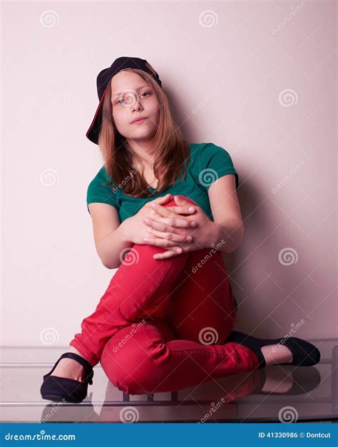 Портрет предназначенной для подростков девушки сидя на таблице Стоковое Фото изображение