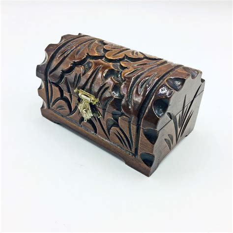 An Intricately Carved Wooden Box On A White Surface With A Key In The