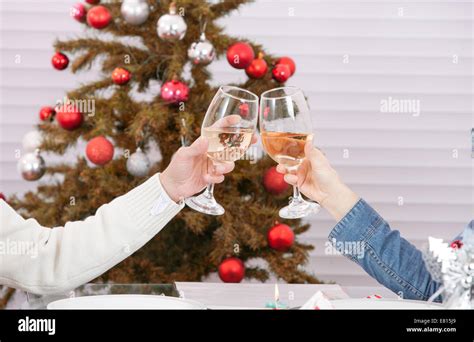 Romantic Couple Hands Holding Glasses Of Champagne And Doing Clink Against Christmas Tree Stock