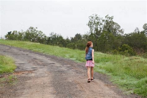 Image Of Young Girl Walking Along A Dirt Road Austockphoto