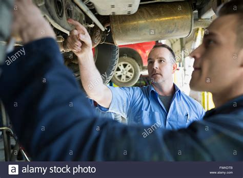 Mechanics Working Under Car In Auto Repair Shop Stock Photo Alamy
