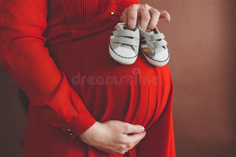 pregnant woman in red flying dress holding her belly close up photo of pregnancy stock image