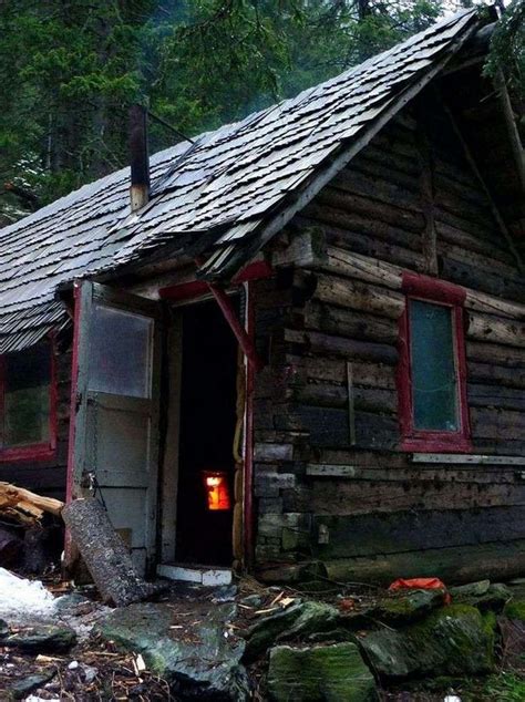 An Old Log Cabin In The Woods Is Lit By A Small Candle And Some Rocks