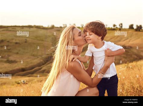 A Mother Kisses Her Son In Nature In The Summer Stock Photo Alamy